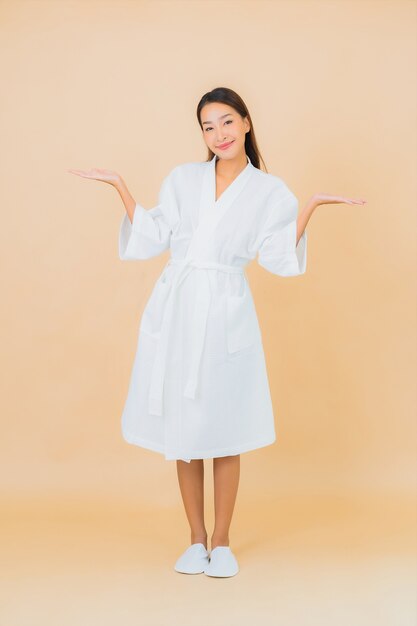 Portrait beautiful young asian woman wearing bathrobe with smile on beige
