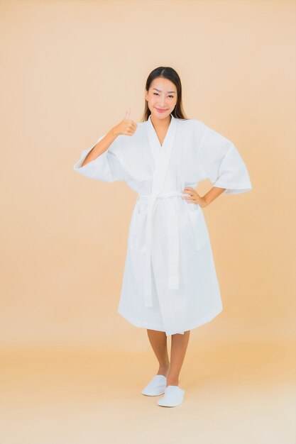 Portrait beautiful young asian woman wearing bathrobe with smile on beige