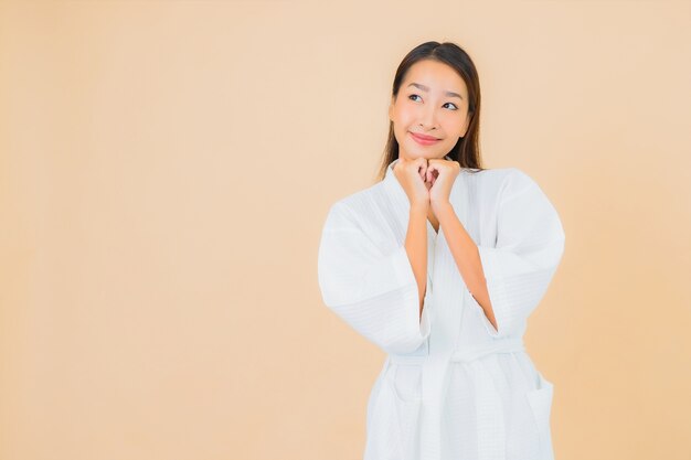 Portrait beautiful young asian woman wearing bathrobe with smile on beige