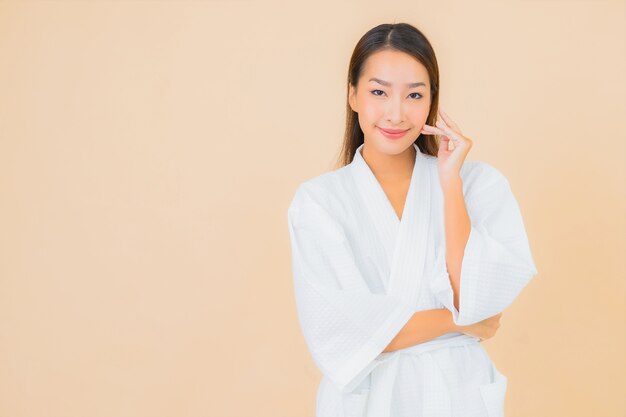 Portrait beautiful young asian woman wearing bathrobe with smile on beige