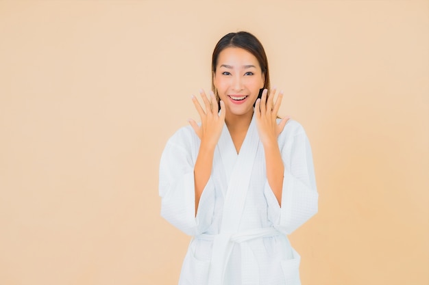 Portrait beautiful young asian woman wearing bathrobe with smile on beige