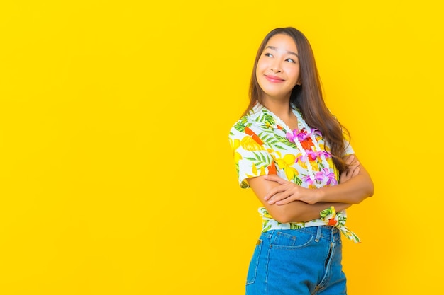 Portrait of beautiful young asian woman wearing colorful shirt on yellow wall