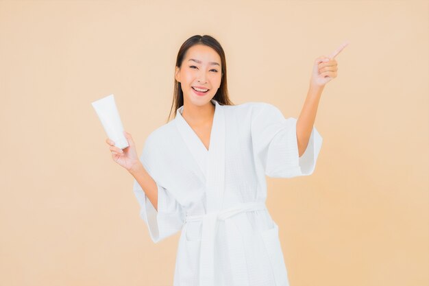 Free photo portrait beautiful young asian woman with bottle lotion and face cream on beige