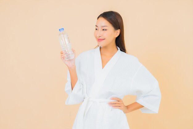 Portrait beautiful young asian woman with bottle water for drink on beige