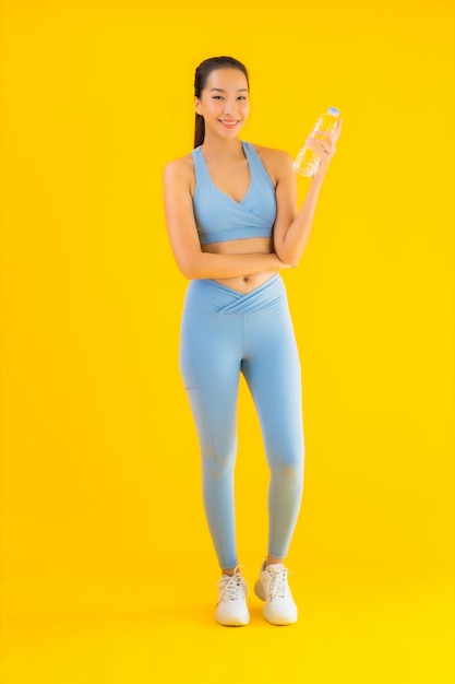 Portrait beautiful young asian woman with bottle water on yellow