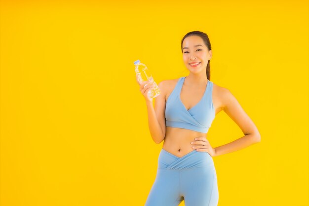 Portrait beautiful young asian woman with bottle water on yellow