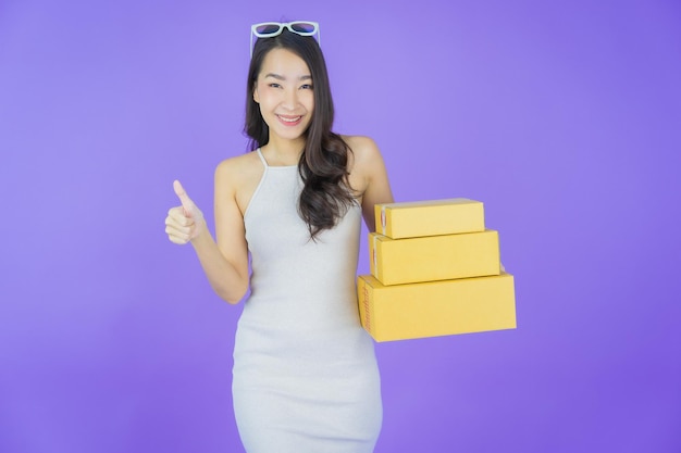 색상 배경에 배송할 준비가 된 상자를 가진 아름다운 젊은 아시아 여성 초상화