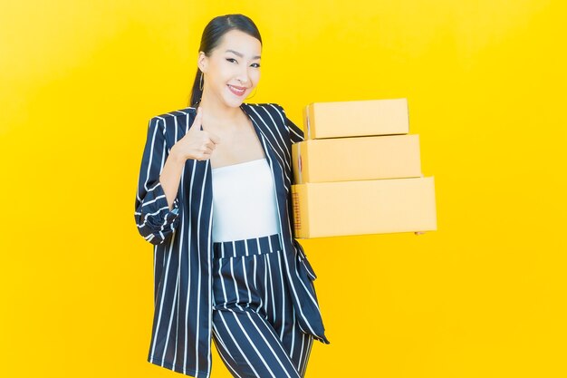 Портрет красивой молодой азиатской женщины с коробкой, готовой к отправке на цветном фоне