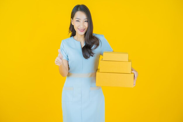 Портрет красивой молодой азиатской женщины с коробкой, готовой к отправке на цветном фоне