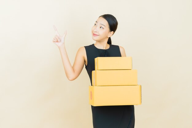 Portrait beautiful young asian woman with box ready for shipping on color wall