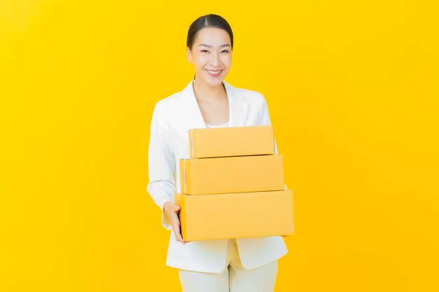 Portrait beautiful young asian woman with box ready for shipping on color wall