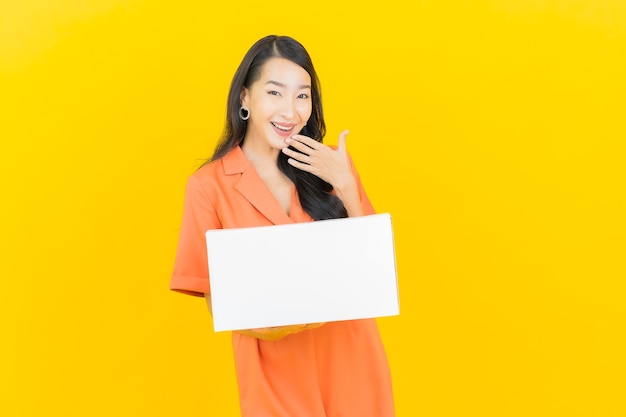 Portrait beautiful young asian woman with box ready for shipping on yellow