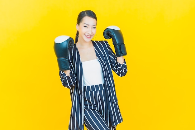 Portrait beautiful young asian woman with boxing glove on color background