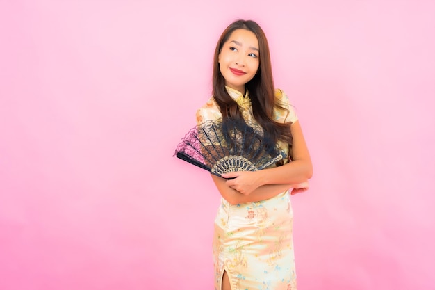 Portrait beautiful young asian woman with chinese new year concept and fan on color wall