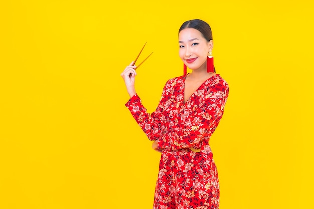 Portrait beautiful young asian woman with chopsticks on color isolated wall