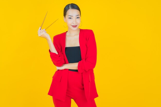 Portrait beautiful young asian woman with chopsticks on yellow