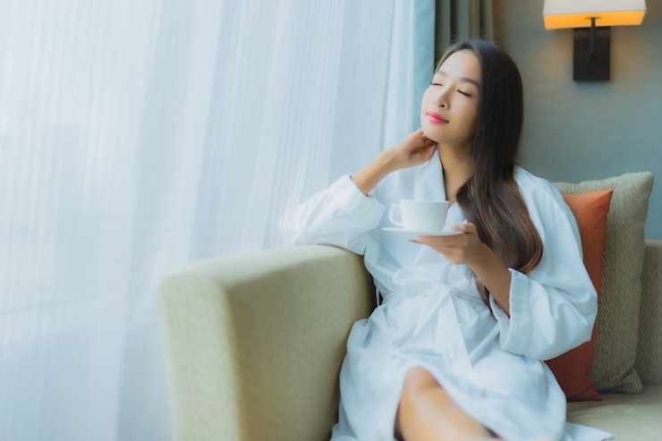 無料Photo ソファの上のコーヒーカップと美しい若いアジア女性の肖像画
