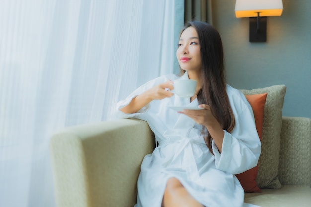 세로 소파에 커피 컵과 아름 다운 젊은 아시아 여자