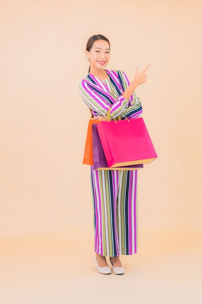 Женщина портрета красивая молодая азиатская с красочной хозяйственной сумкой на цвете