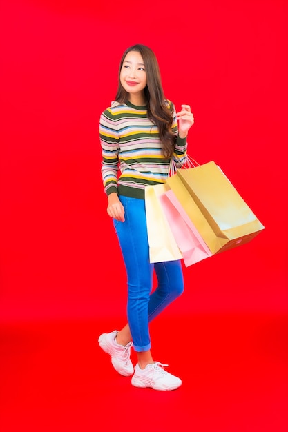 赤い壁にカラフルなショッピングバッグと肖像画美しい若いアジアの女性