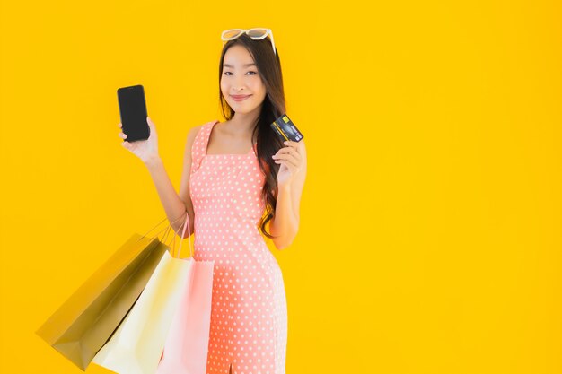 スマートフォンとクレジットカードとカラフルなショッピングバッグの美しい若いアジア女性の肖像画