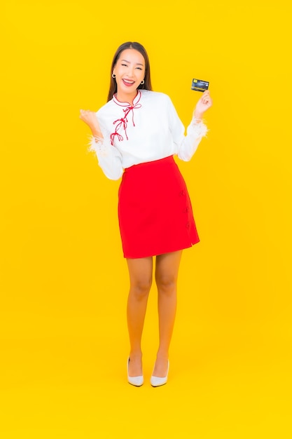 노란색에 온라인 쇼핑을위한 신용 카드로 세로 아름다운 젊은 아시아 여자