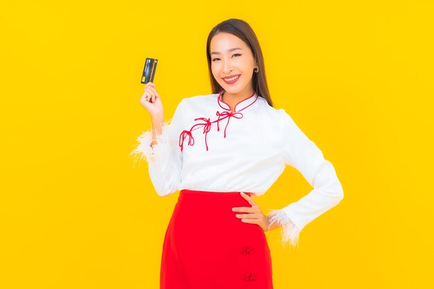 Портрет красивой молодой азиатской женщины с кредитной картой для онлайн-покупок на желтом