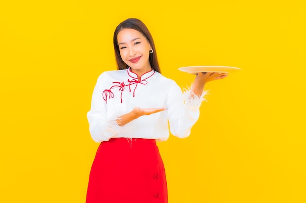 Ritratto bella giovane donna asiatica con piatto piatto su yellow