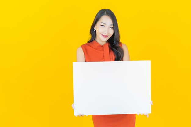 Portrait beautiful young asian woman with empty white billboard on yellow