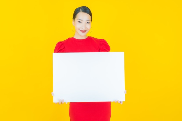 Portrait beautiful young asian woman with empty white billboard on yellow