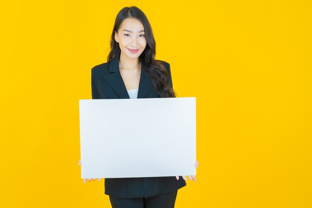 Portrait beautiful young asian woman with empty white billboard on yellow