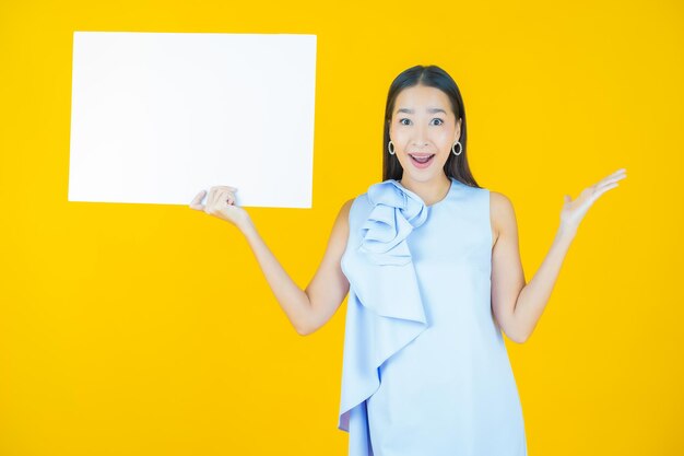 Portrait beautiful young asian woman with empty white billboard on yellow