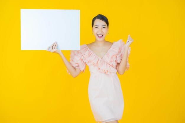 Portrait beautiful young asian woman with empty white billboard on yellow