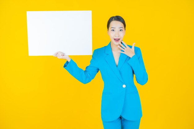 Portrait beautiful young asian woman with empty white billboard on yellow