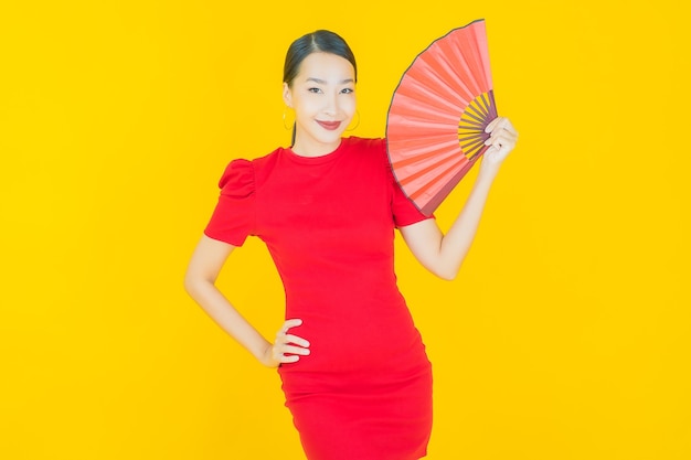 Free photo portrait beautiful young asian woman with fan on yellow