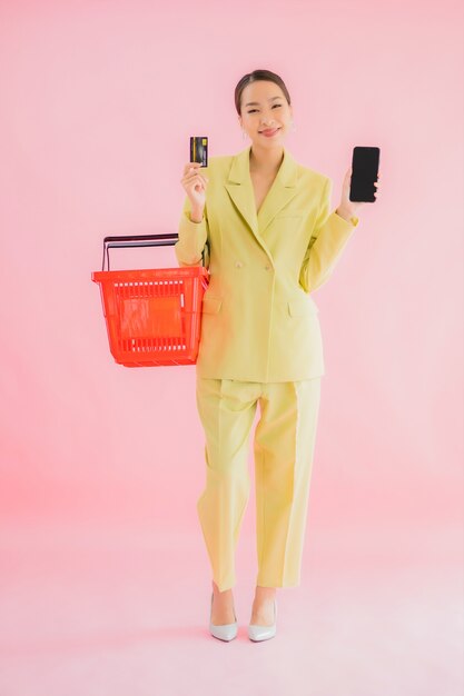 Portrait beautiful young asian woman with grocery basket from supermarket on color