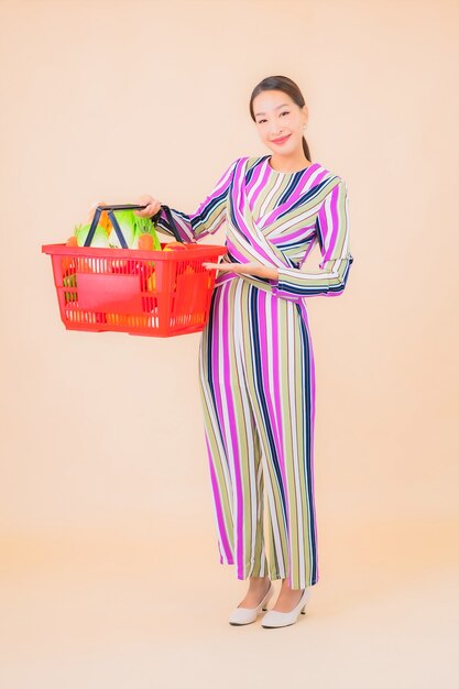 Portrait beautiful young asian woman with grocery basket from supermarket on color