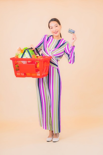 Portrait beautiful young asian woman with grocery basket from supermarket on color