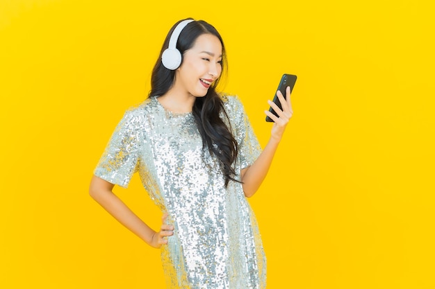 Portrait beautiful young asian woman with headphone and smart phone for listen music on yellow