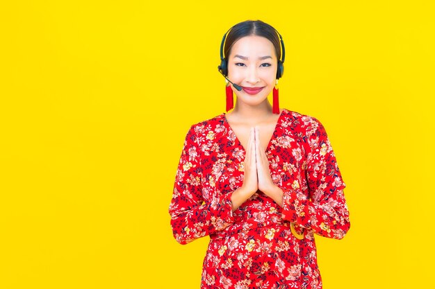 Portrait beautiful young asian woman with headset for customer call center care on yellow wall