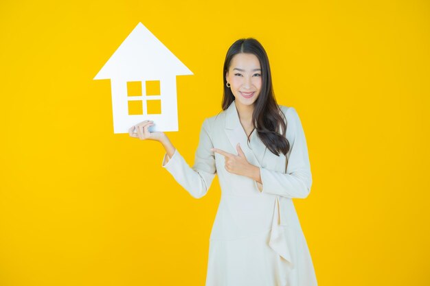 Portrait beautiful young asian woman with house or home paper sign on color background