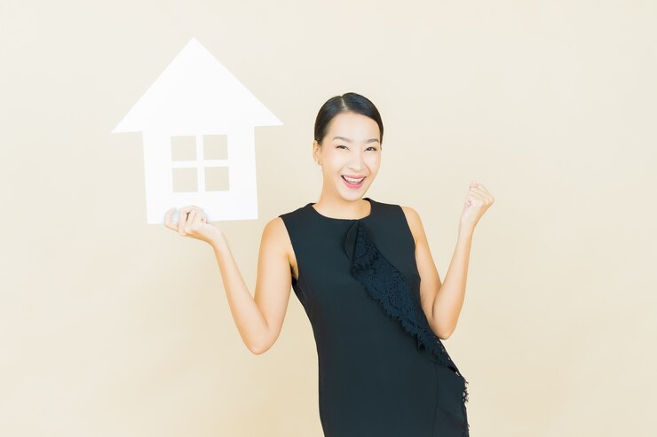 免費 Photo 美麗的年輕亞洲女子的肖像與房子或家紙標誌在彩色牆上