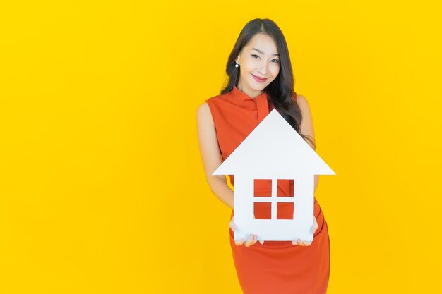 노란색에 집이나 집 종이 표지판이 있는 아름다운 젊은 아시아 여성 초상화