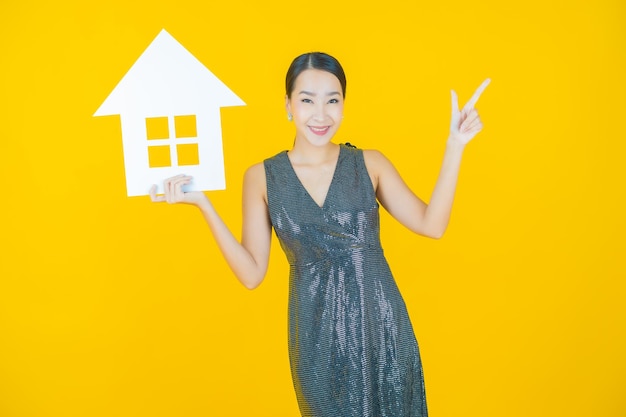 Portrait beautiful young asian woman with house or home paper sign on yellow