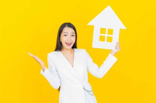 Free photo portrait beautiful young asian woman with house or home paper sign