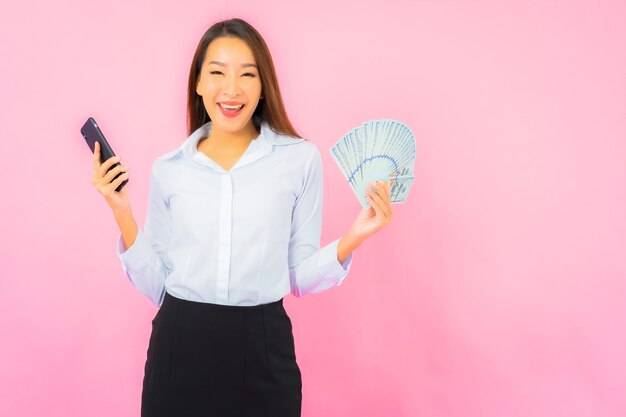 Portrait beautiful young asian woman with a lot of cash and money on pink wall