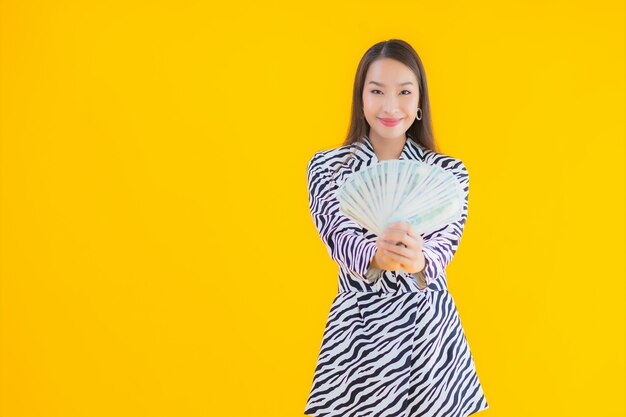 Portrait beautiful young asian woman with a lot of cash and money on yellow