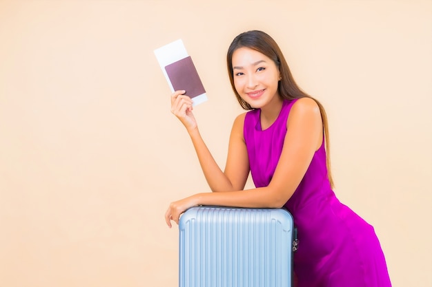 Portrait beautiful young asian woman with luggage and airplate ticket on color background