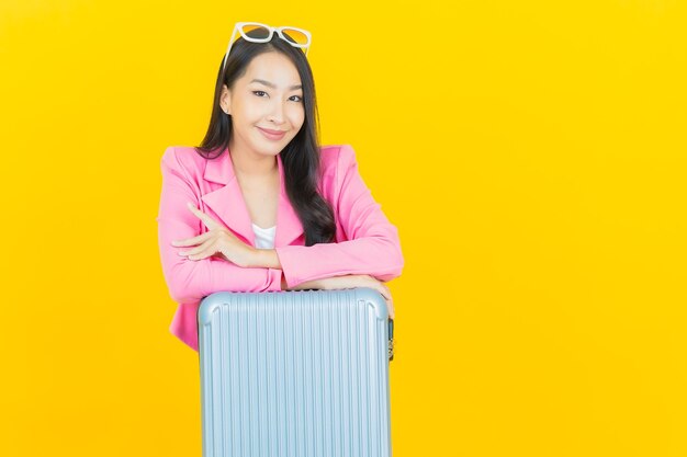 Портрет красивой молодой азиатской женщины с багажной сумкой и паспортом, готовыми к путешествию
