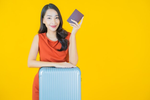 旅行の準備ができて荷物バッグとパスポートを持つ肖像画の美しい若いアジアの女性